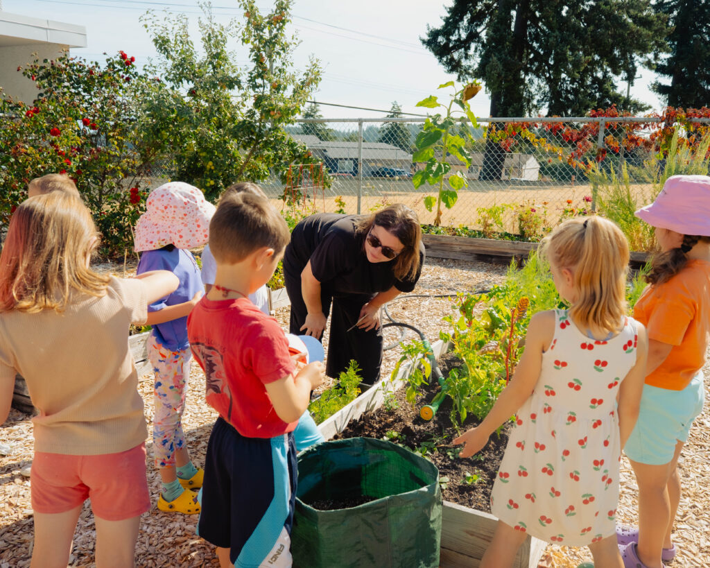 Enfants participant à des activités de jardinage au camp d'été francophone à Nanaimo, en plein air.