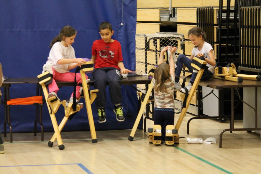 Participants à un camp de jour cirque apprenant à marcher sur des échasses.